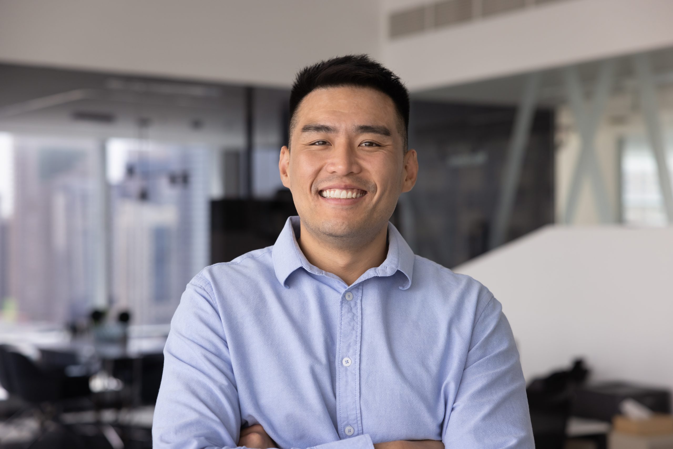 East Asian man in blue shirt smiling at the camera